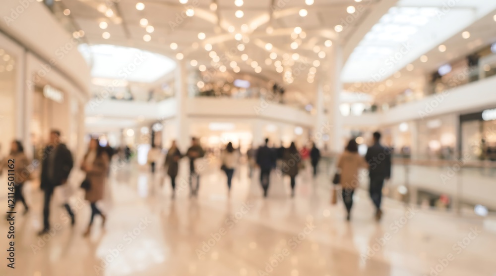 Obraz premium Blurred view of busy shopping mall with customers walking in a bright spacious retail environment featuring modern architecture and elegant overhead lighting for commercial use