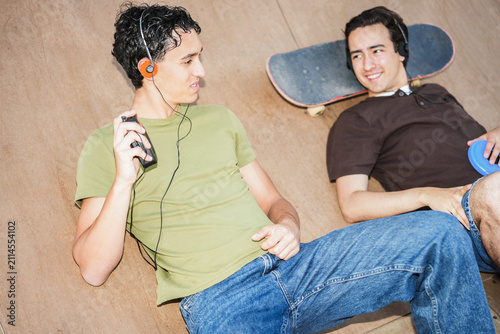 Two young friends listening music with cassette player and cd player - New trend people lifestyle using vintage analog devices - UGC flash content - Focus on left man face