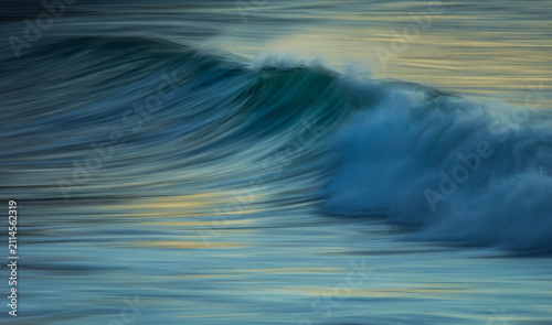 Canvastavla Ocean wave at sunrise with spray at the crest at slow shutter speed