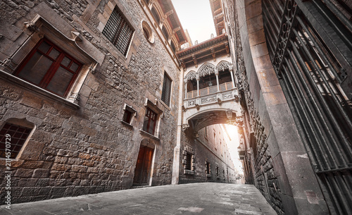 Barcelona, Spain. Barri Gotic Quarter. Antique Bridge between stone walls of medieval buildings in in old town. Famous touristic landmark and travel destination. Sunset evening street perspective.