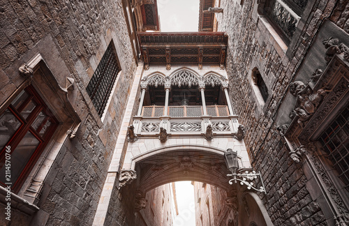 Barcelona, Spain. Barri Gotic Quarter. Antique Bridge between stone walls of medieval buildings in in old town. Famous touristic landmark and travel destination. Sunset evening street perspective.