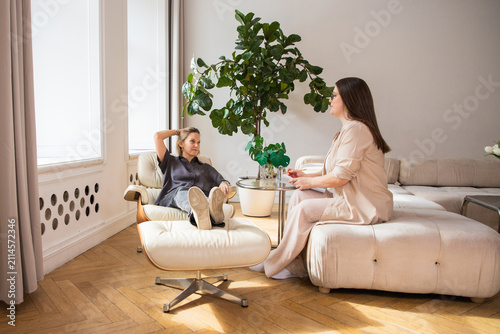 Woman psychologist talking with a client in a modern office. Mental health therapy session with a patient sitting in a lounge chair. Professional counseling and psychological support.