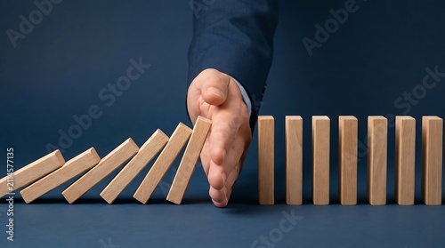 Businessman stopping falling dominoes