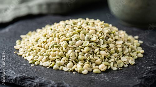 Pile of dried split green peas on a dark textured slate background