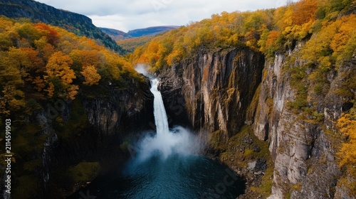 Majestic waterfall cascading into a serene pool, surrounded by vibrant autumn foliage on steep cliffs. A breathtaking natural landscape showcasing nature's grandeur