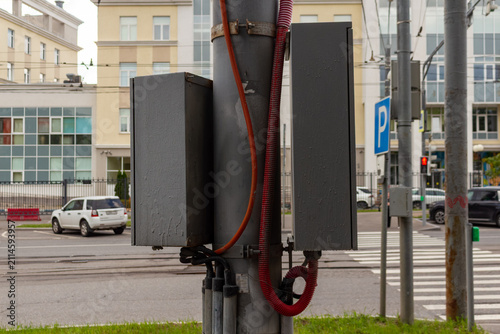 Fotografie Electrical control boxes mounted on metal pole in urban street environment