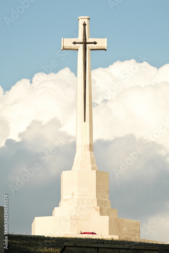 christian marble cross against clouds in the blue sky, Agira, Sicily, Italy
