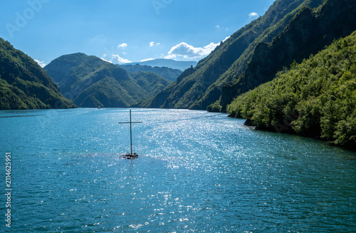 Wooden cross standing in the waters of Komani Lake Albania