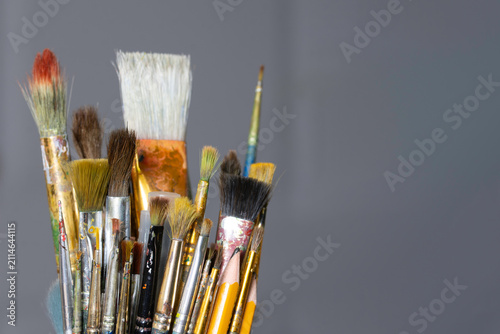Studio still life with mixed paintbrushes in a dark container