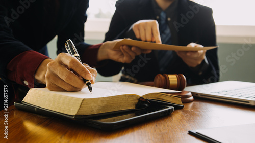 Lawyers Reviewing Legal Documents and Taking Notes During Client Consultation in Modern Law Office