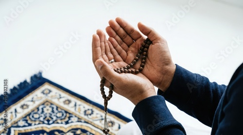 Close up of a person holding prayer beads while making dua with open hands in front of a mosque