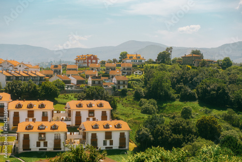 Obraz na plátně Traditional modern Basque village with white houses and orange tile roofs nestled on green hills in countryside near Bilbao, Basque Country, Northern Spain