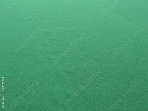 Close-up of a smooth green felt fabric texture with a soft matte finish and subtle folds, creating an abstract and minimal background.