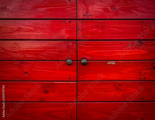 A red wooden wall with horizontal panels and two metal bolts