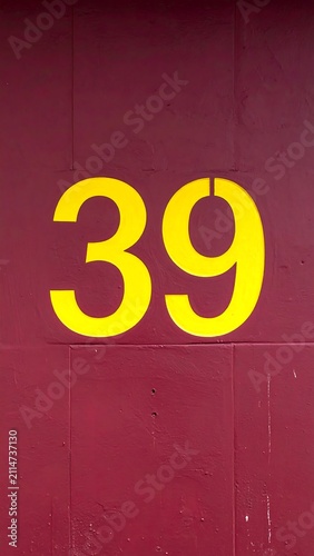 A red-painted concrete wall with a large yellow number 39 on it