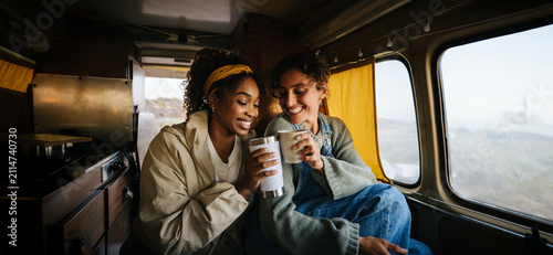 Friends share coffee and smiles inside a cozy van
