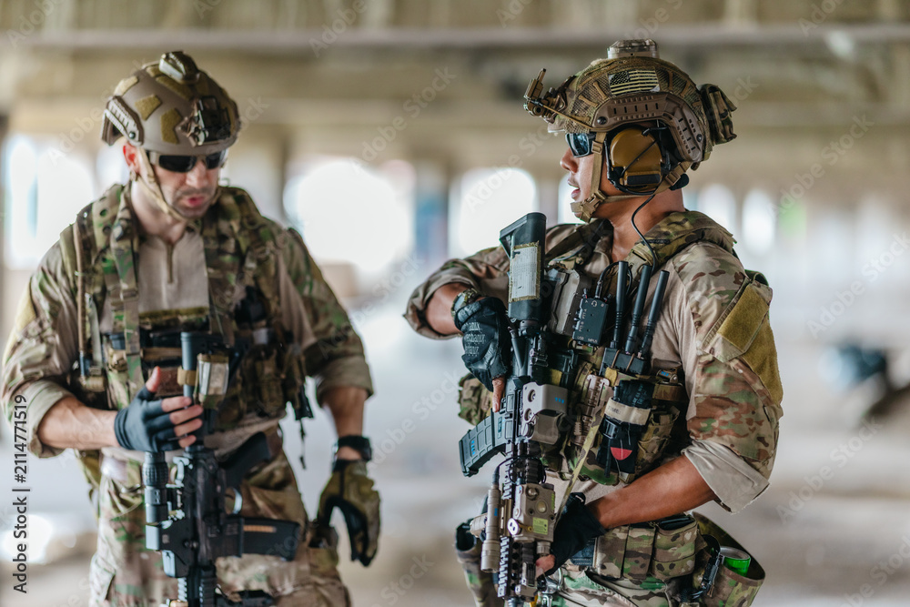 Fototapeta premium Military tactical operator holds rifle while clearing abandoned concrete building interior