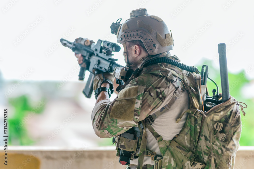 Fototapeta premium Military tactical operator holds rifle while clearing abandoned concrete building interior