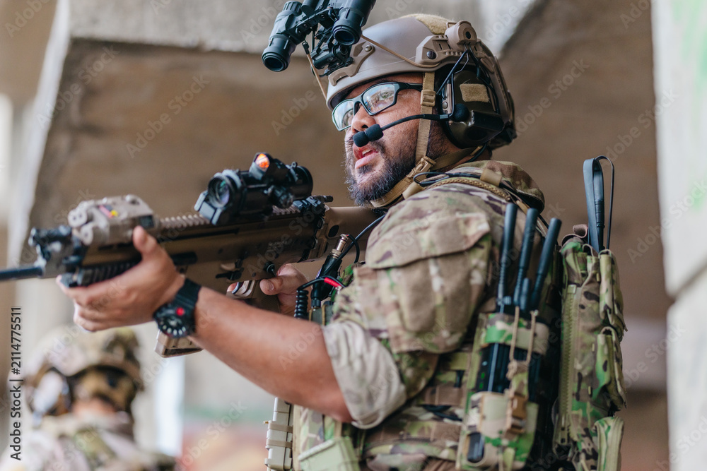 Fototapeta premium Military tactical operator holds rifle while clearing abandoned concrete building interior