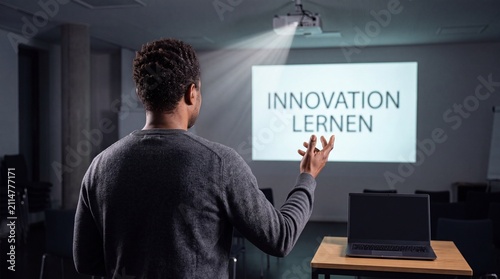 Mann gestikuliert über die Schulter zur Projektion mit Schriftzug Innovation Lernen im dunklen Seminarraum