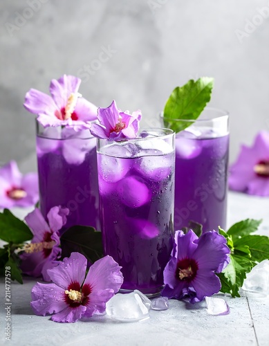 A refreshing drink with purple liquid and flowers in glasses on a table