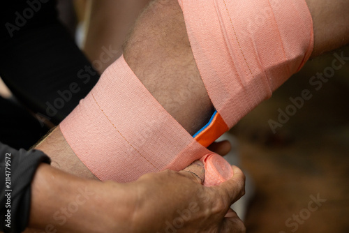 Obraz na plátně Elastic therapeutic bandage wrapped around athlete knee with hands adjusting wra