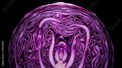 Close up top view of a halved red cabbage vegetable showing the intricate natural patterns of purple and white layered leafy textures against a black background