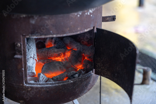 Fotografie Glowing charcoal inside small metal charcoal stove with open door, warm orange e