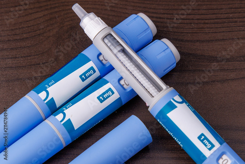 Blue Semaglutide GLP-1 pen injector resting on a dark wooden table background, modern drug therapy for obesity and diabetes control concept