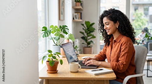 Young woman working on laptop at home. Female professional using computer in modern workspace.