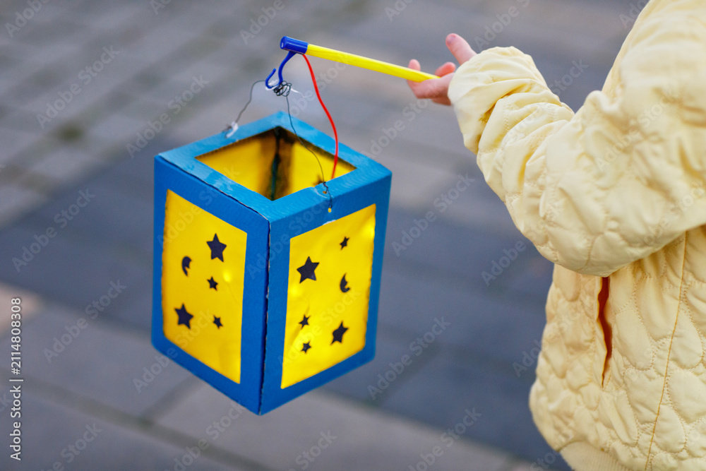Obraz premium Closeup of little preschool kid girl holding selfmade traditional lanterns with candle for St. Martin procession. child happy about family parade in kindergarten. German tradition Martinsumzug