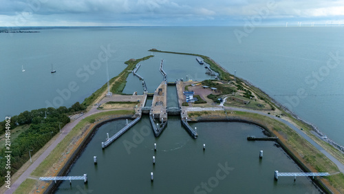 Aerial view of the Lorentz locks on the Afsluitdijk surrounded by wide open water under a cloudy sky. Dutch water management scene showing sluice gates, waterways, breakwaters and coastal infra.
