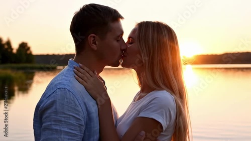 Romantic Couple Kissing at Sunset by the Lake During Golden Hour