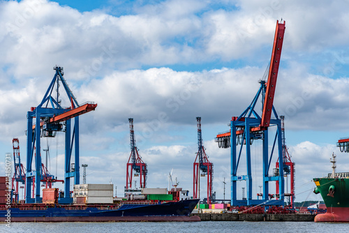 Container Cargo Ships and Gantry Cranes at a Commercial Seaport Terminal Under Dramatic Cloudy Sky