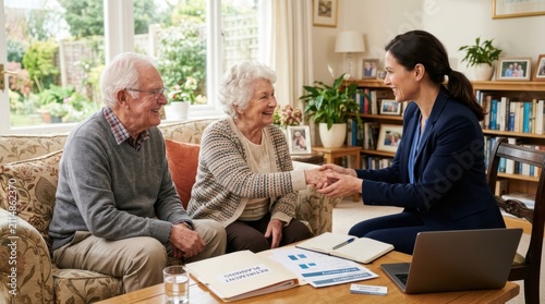 Friendly female financial advisor shaking hands with a happy elderly couple sitting at home during a consultation meeting