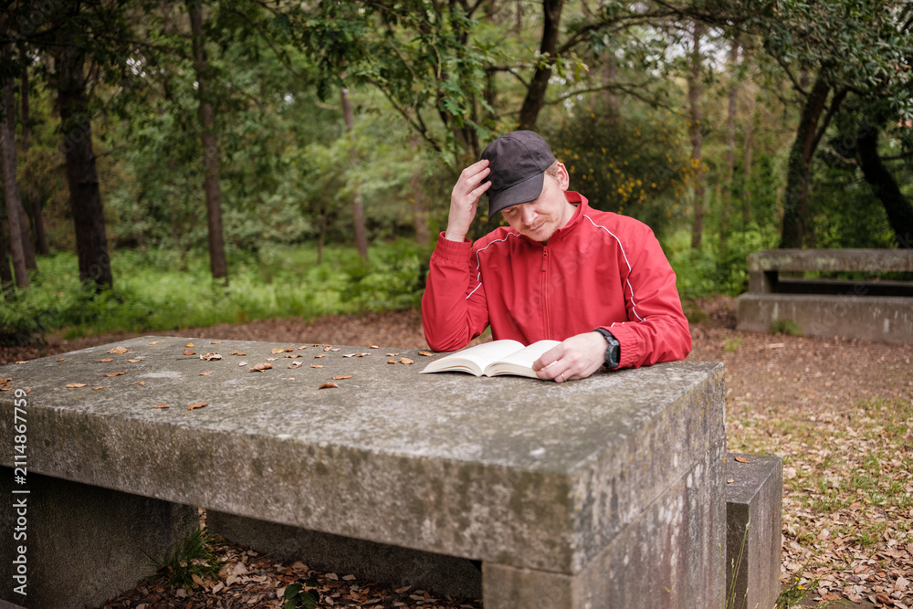 Fototapeta premium Man reading book in park thinking deeply