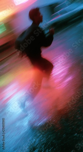 Blurred Walking Figure Night Street Multicolor Neon Light Streaks Rain Panning Shot Portrait