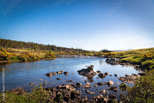 A bright, summer HDR landscape image of the salmon river, the River Naver, flowing through Strathnaver, Sutherland, Scotland.