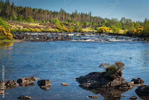A bright, summer HDR landscape image of the salmon river, the River Naver, flowing through Strathnaver, Sutherland, Scotland.