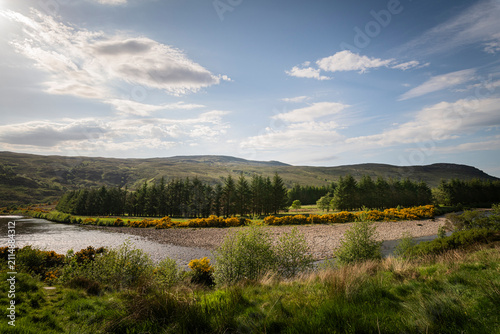 A bright, summer HDR landscape image of Strath More River in Strath More, just north of Altnaharra, Sutherland, Scotland.