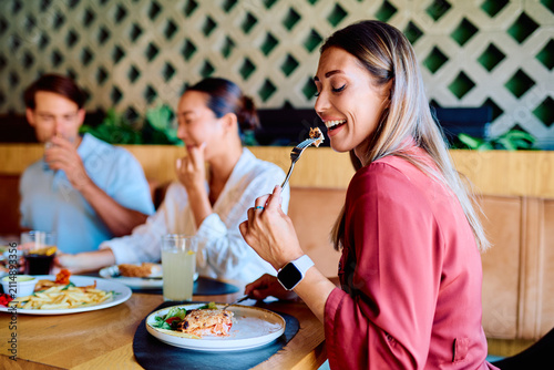 Canvastavla Smiling woman with friends enjoying a meal at a restaurant, sharing conversation