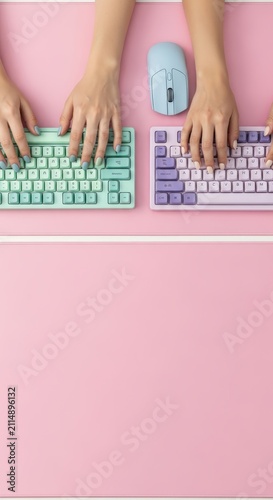 Two people typing on colorful keyboards with a blue mouse on a pink background, top view.