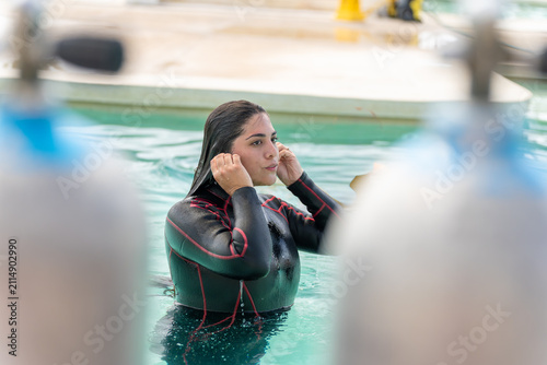 Konstfotografi Woman in wetsuit adjusting diving gear in a pool, preparing for scuba training
