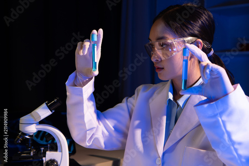 Scientist analyzes a colored liquid to extract the DNA and molecules in the test tubes. Scientists test the chemical reactions of the solution and test biological fluids in test tubes.