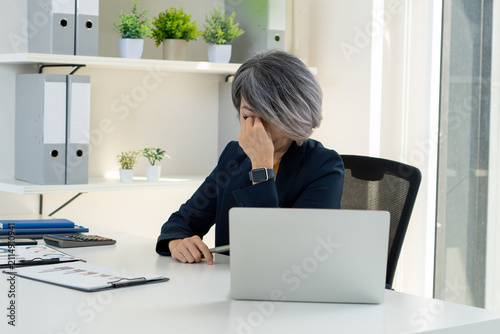 Stressed Businesswoman Rubbing Temples at Office Desk