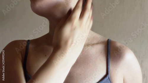 Woman massaging collarbone and neck with a massage ball for pain relief, muscle relaxation, myofascial release, and lymphatic drainage to improve blood circulation