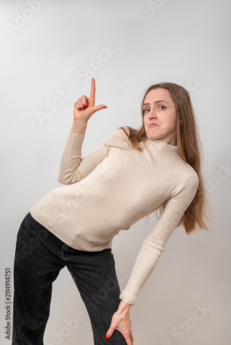 Canvas Print Young woman with long hair making an L hand sign on white background, showing di