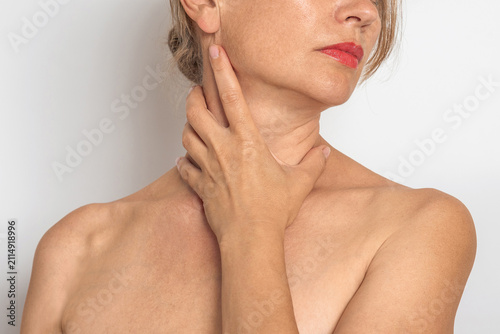 Woman touches neck and collarbone area with hand, checks skin and lymph node area. Women's health.