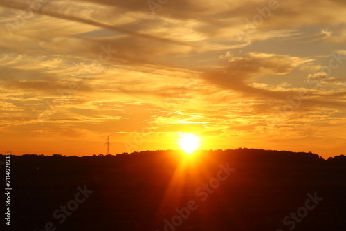 Konstfotografi A dramatic sunset over a silhouetted hill, with vibrant orange and yellow hues p