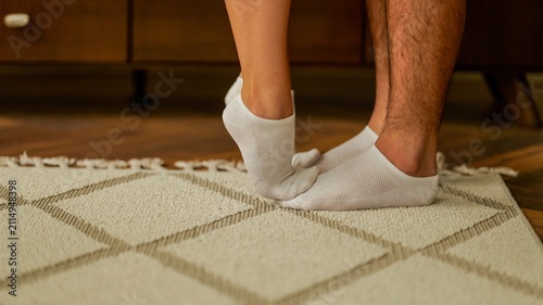 Fotografie Close-up of couple's feet in white socks standing on a rug indoors